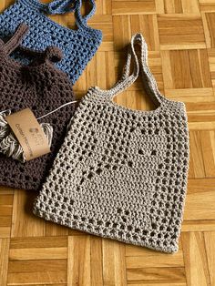 three crocheted bags sitting on top of a wooden floor next to each other