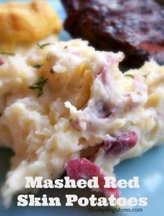 mashed red skin potatoes with raspberries on a blue plate next to meat