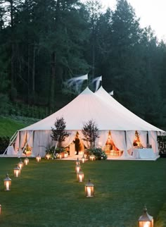 a large white tent with candles in the grass