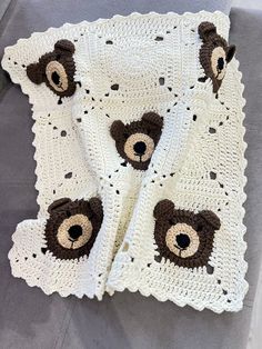 a crocheted teddy bear blanket on top of a gray bed with white sheets