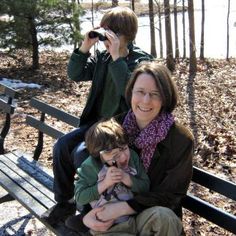 a woman and two children sitting on a bench