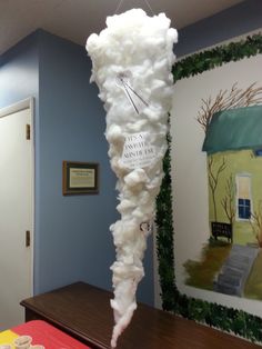 a large piece of paper mache hanging from the ceiling in front of a painting