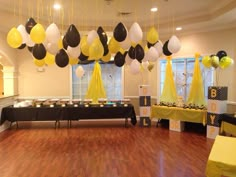 a party hall decorated with balloons and black and white decorations, yellow tablecloths