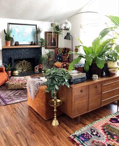 a living room filled with lots of furniture and plants on top of it's wooden floors