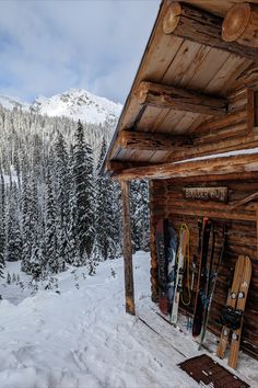 there are many skis and snowboards in front of the cabin on the mountain