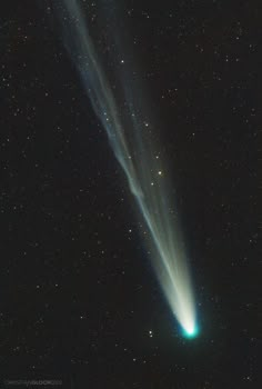 an image of a comet in the sky with stars around it and green light coming from its tail