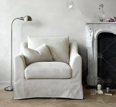 a white chair sitting next to a fireplace with a lamp on it's side