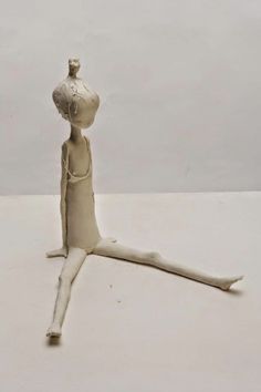 a clay figure sitting on top of a white surface