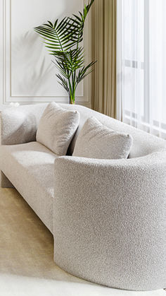 a living room filled with white furniture next to a tall potted plant on top of a wooden table