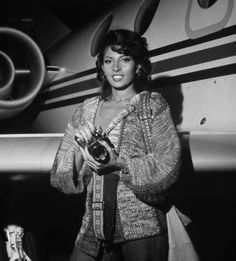 a black and white photo of a woman holding a camera in front of an airplane