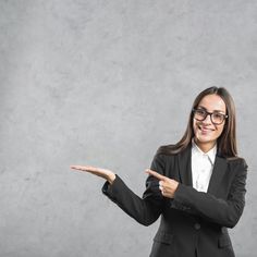 a woman in a business suit pointing to something with her hand and smiling at the camera