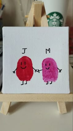 two little red and pink cartoon characters on a white canvas with a wooden easel