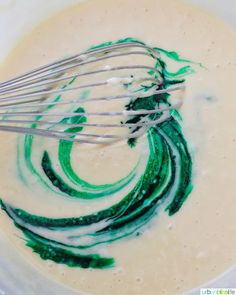 a bowl filled with green liquid and whisk