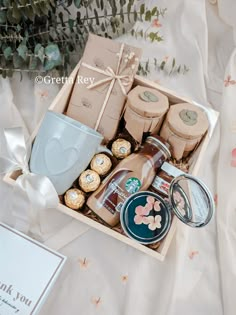 a gift box filled with coffee, cookies and other items on a table next to flowers