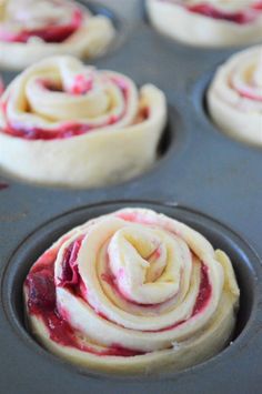 some cupcakes that are sitting in a muffin tin with red and white icing