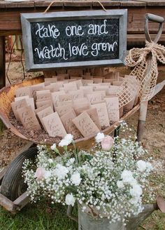 an old wagon filled with lots of flowers next to a sign that says take one and watch love grow