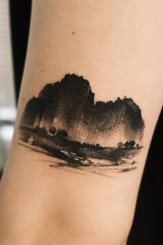 a black and white photo of mountains on the side of a woman's leg