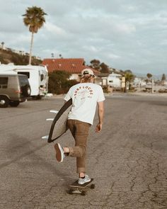 a man riding a skateboard down a street next to a campervane