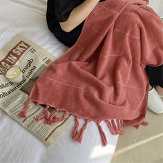 a woman laying on top of a bed covered in a pink blanket and holding a lit candle