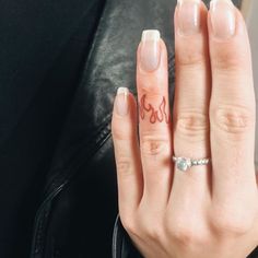 a woman's hand with a ring on it and the word love written in red ink