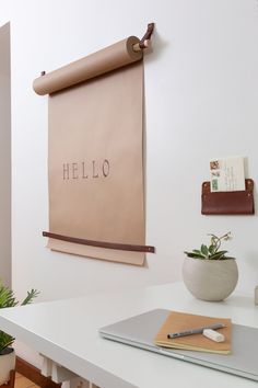 a white desk topped with a laptop computer next to a wall mounted sign that says hello