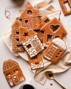 gingerbread cut out houses are on a plate with some coffee and spoons next to them