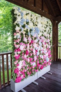 a large flower wall on the side of a wooden building with white and pink flowers