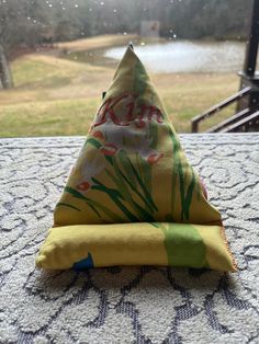 a triangle shaped pillow sitting on top of a table next to a window sill