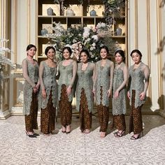 a group of women standing next to each other in front of a white and gold wall