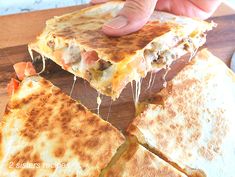 someone is taking a slice of quesadilla from the cutting board