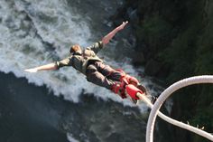 a man is in mid air while bungeeing over the water