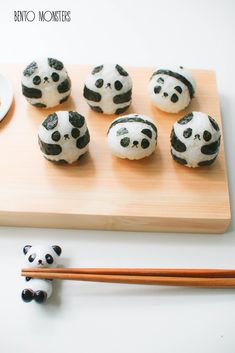 there are many panda cookies on the wooden board with chopsticks next to it