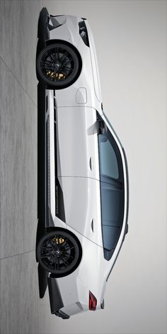 the rear end of a white car with black wheels and rims on it's tires