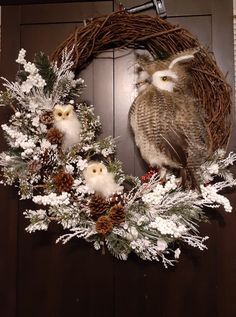 an owl is sitting on top of a wreath with pine cones and snowflakes