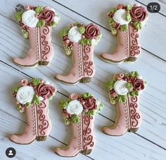 four decorated cookies in the shape of boots with flowers on them, sitting on a white wooden surface