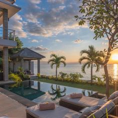 the sun is setting over an outdoor pool and patio area with lounge chairs overlooking the ocean