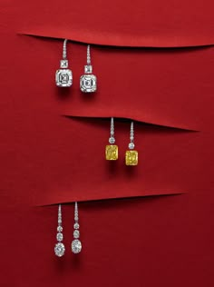 three pairs of diamond earrings on red paper with white and yellow diamonds in the middle