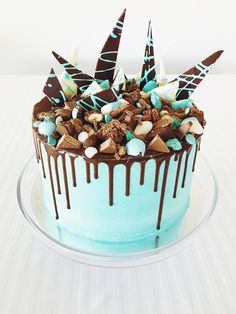 a blue cake with chocolate and marshmallows on top, drizzled in chocolate