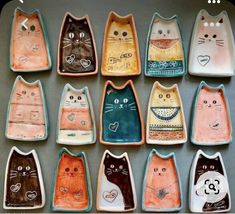 nine ceramic cats are sitting in rows on the table, each painted with different colors