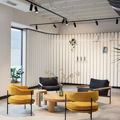 an office with yellow chairs and black couches in front of a white vertical wall