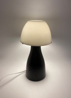 a black table lamp with a white light on it's side and a cord attached to the base