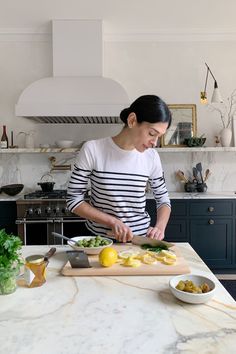 a woman cutting up some food on top of a kitchen counter