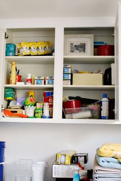 an organized kitchen with white cabinets and shelves