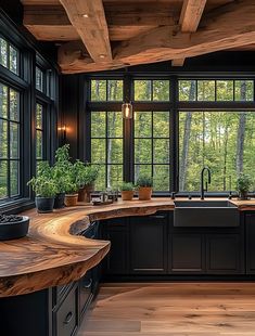 a kitchen with black cabinets and wooden counter tops in front of large windows that look out onto the woods