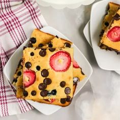 two white plates topped with dessert squares and strawberries