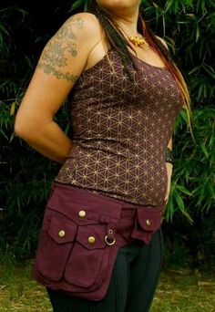 a woman with tattoos is standing in front of some trees and grass wearing a purple top