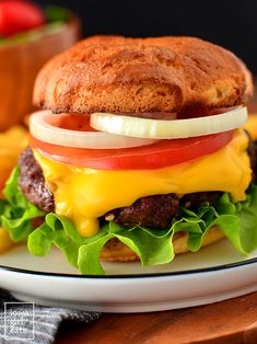 a cheeseburger with tomato, lettuce and onion on a plate next to some fries