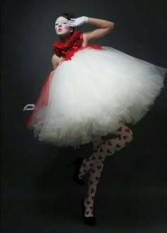 a woman dressed in white and red poses for the camera with her hands on her hips