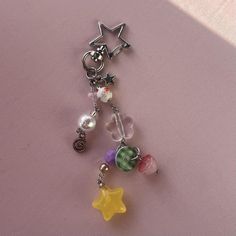 a close up of a key chain on a pink surface with a star charm hanging from it's side