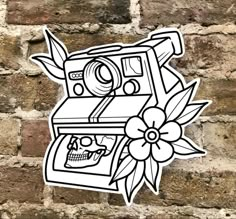 a sticker on the side of a brick wall with a camera and skull in it